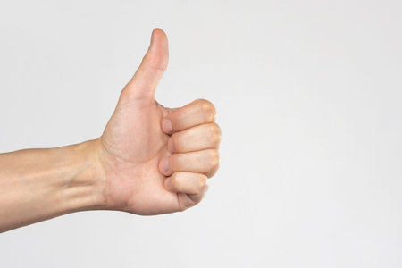 Hand with raised thumb on a white background. Hand showing like. The concept of all is well.