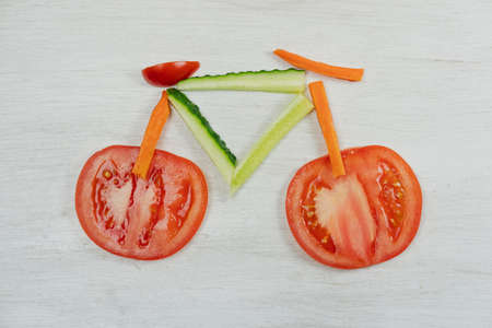 Vegetables lined up in the shape of a bicycle on a white background. The concept of weight loss, diet, healthy eating, healthy lifestyleの写真素材