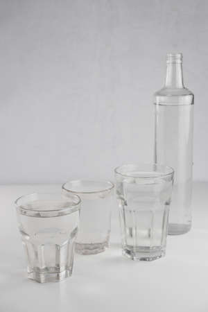 Several glasses and a bottle of clean water on a white backgroundの写真素材