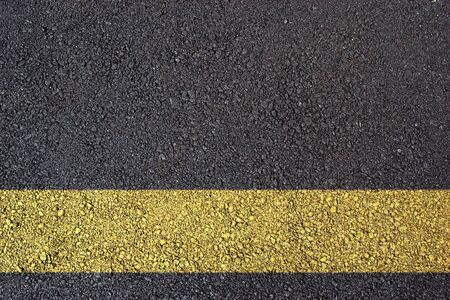 Dark asphalt surface photo with yellow lineの写真素材