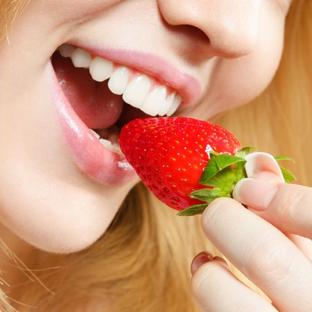 Happy young woman eating mellow strawberryの写真素材