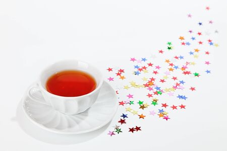 Black tea in white cup with stars confetti aroundの写真素材