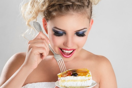 Beautiful blonde woman eating a cake slice on plateの写真素材