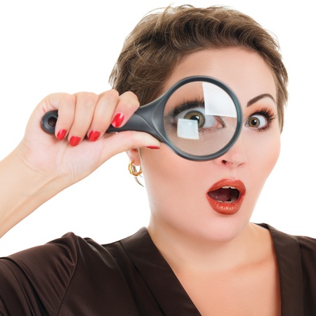 Beautiful surprised woman looking through a magnifying glass isolated over white backgroundの写真素材