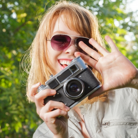 Young woman making photos with vintage film camera at summer green park.の写真素材