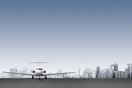 Commercial airliner on runway in front of modern cityの写真素材