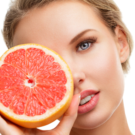 Young blonde woman with grapefruit in her hands studio portrait isolated on white backgroundの写真素材