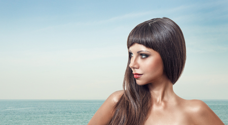 Portrait of beautiful young woman at tropical beach with sea water in backgroundの写真素材