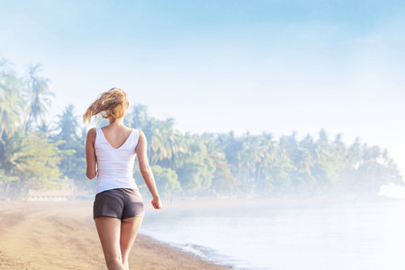 Young woman jogging on the beach. Rear viewの写真素材