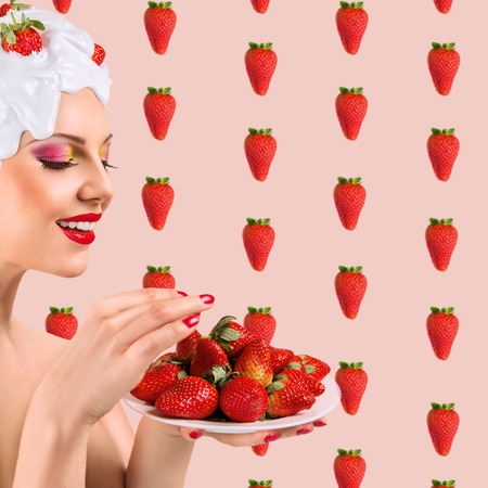 Young woman with hairstyle made from milk and strawberry eating red ripe berriesの写真素材