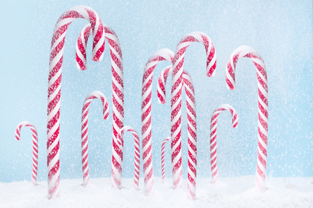 Christmas candy peppermint cane with snowfall on blue backgroundの写真素材