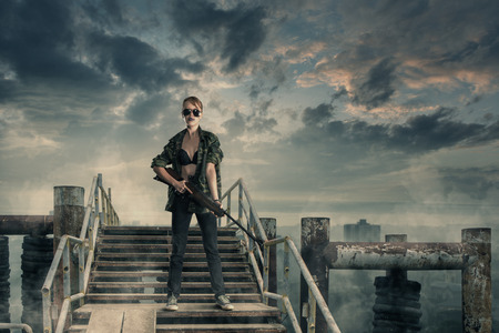 Apocalyptic portrait of young sexy woman warrior against of ruined abandoned cityの写真素材