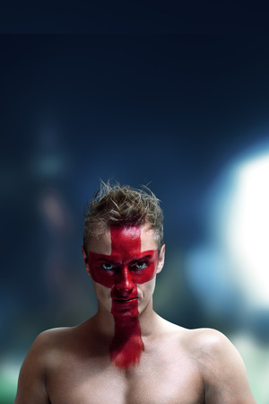 Football fan with England flag painted on his face in front of night stadiumの写真素材