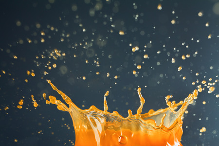 Orange juice crown splash spraying over dark backgroundの写真素材