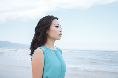 Young beautiful asian woman is walking along the tropical sea beachの写真素材