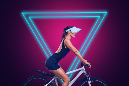 Young woman riding on bicycle in front of modern neon glowing design backgroundの写真素材
