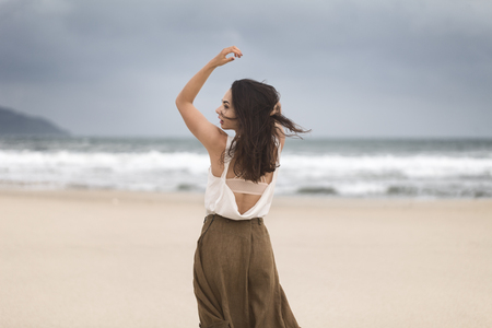 Lifestyle portrait of happy carefree woman walking on the beach with space for text.の写真素材
