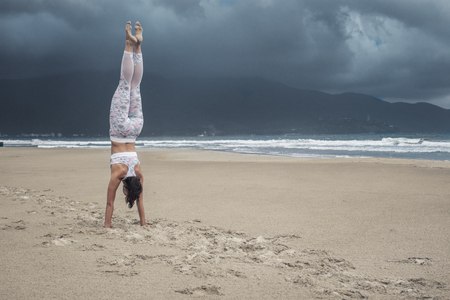 Young sporty slim woman doing yoga exercise on sand of the tropical sea beach with space for textの写真素材