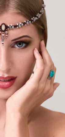 A stunning close-up portrait of a young, beautiful woman gracefully adorning herself with jewelry. An exquisite portrayal of elegance and beauty.の写真素材