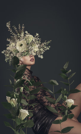 A sensual woman with floral headdress poses amidst lush leaves and blooms in an artistic botanical portrait.の写真素材
