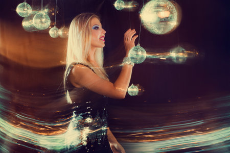 Artistic nightclub atmosphere young woman with mirror balls and motion blur effects. for party promotions, entertainment industry, nightlife advertising, or fashion marketing materials.の写真素材