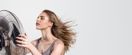 Beautiful woman in front of fan, hair blowing. Use for articles about summer heat, seasonal affective disorder or cooling devices.の写真素材