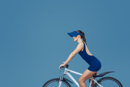 A female athlete on a bicycle in a studio. for themes of sport, fitness, health, training, energy, and an active lifestyle.の写真素材