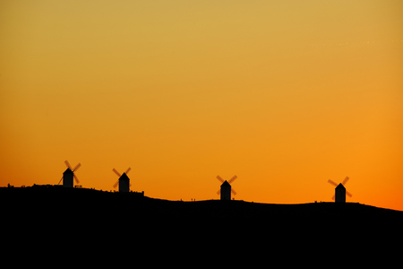 Silhouettes of the Mills of La Mancha and people a sunset.の写真素材