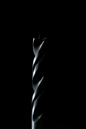 Wood spiral drill bit with black background and vertical framing