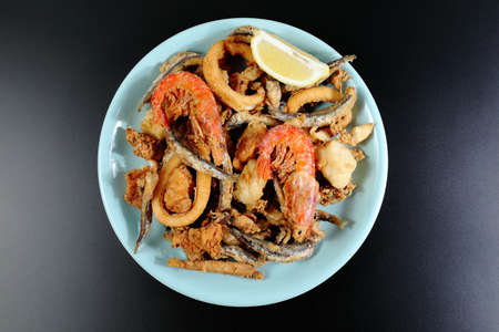 Fried fish portion on black plate and black backgroundの写真素材
