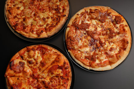Three pizzas on black background viewed from aboveの写真素材