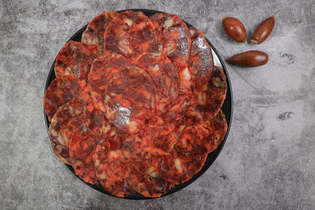 Portion of 100% acorn-fed Iberian chorizo from Extremadura decorated with acorns with dark gray...