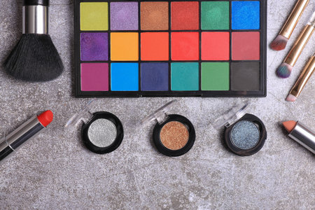 Makeup palette top view with brushes and lipstick