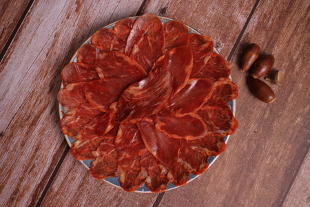 Portion of 100% acorn-fed Iberian loin on wooden table, adorned with acornsの写真素材