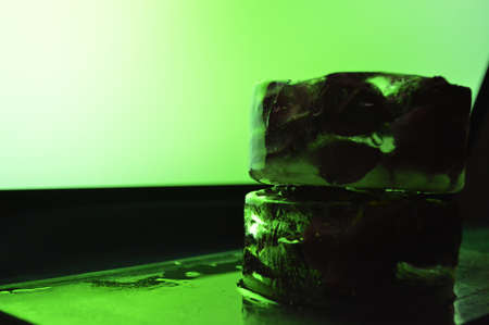 Roses frozen in ice on black background and field of green neon lightの写真素材