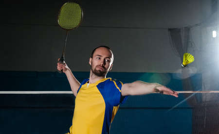 Bearded  badminton player in sport outfit making a racket swing. Artistic studio lighting and lens flare effect.の写真素材
