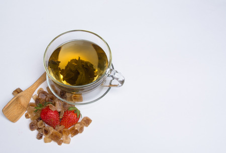 mug of hot green tea with red strawberries and sugarの写真素材