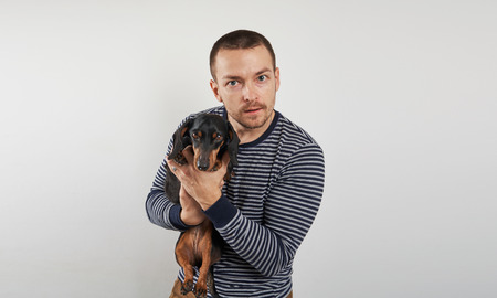 man holds a Dachshund in his handsの写真素材