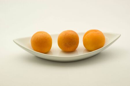 Apricots on plate on white backgroundの写真素材