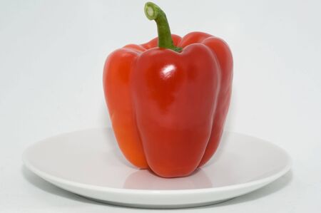 Fresh red pepper on a plate on a white background closeupの写真素材