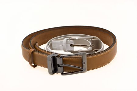 White women's and brown men's leather belts with buckle  on a white backgroundの写真素材