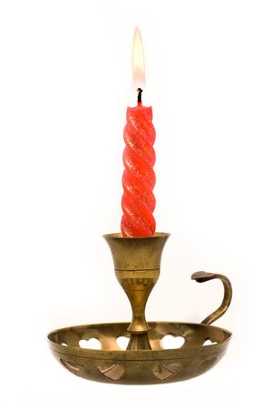 Red candle lit in copper holder on a white backgroundの写真素材