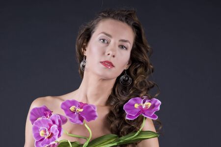 Portrait of a  young beautiful woman with long wavy hair on a gray background closeupの写真素材