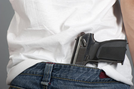 Gun inserted by the waist of jeans at the young man