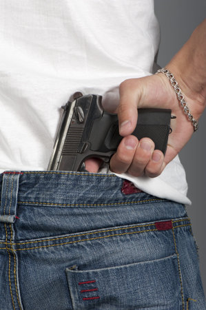 Gun inserted by the waist of jeans at the young man