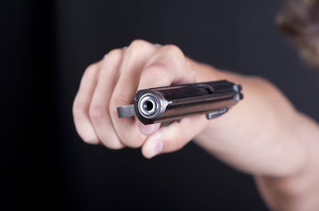 Old pistol in a male hand on black background closeup