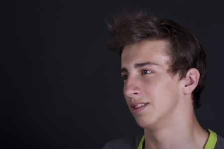 A young man in a vest on a black background in the studioの写真素材