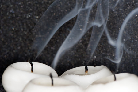 Four outstanding paraffin candles on a black background close-upの写真素材