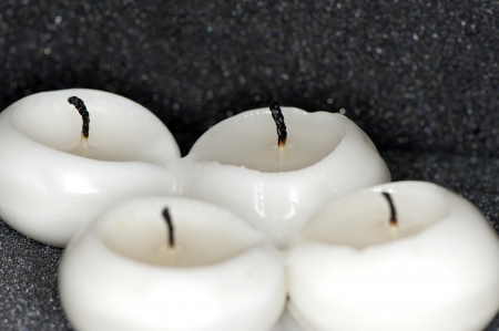 Four outstanding paraffin candles on a black background close-upの写真素材