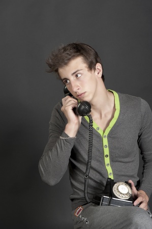 Young guy talking on the old phone on a black backgroundの写真素材